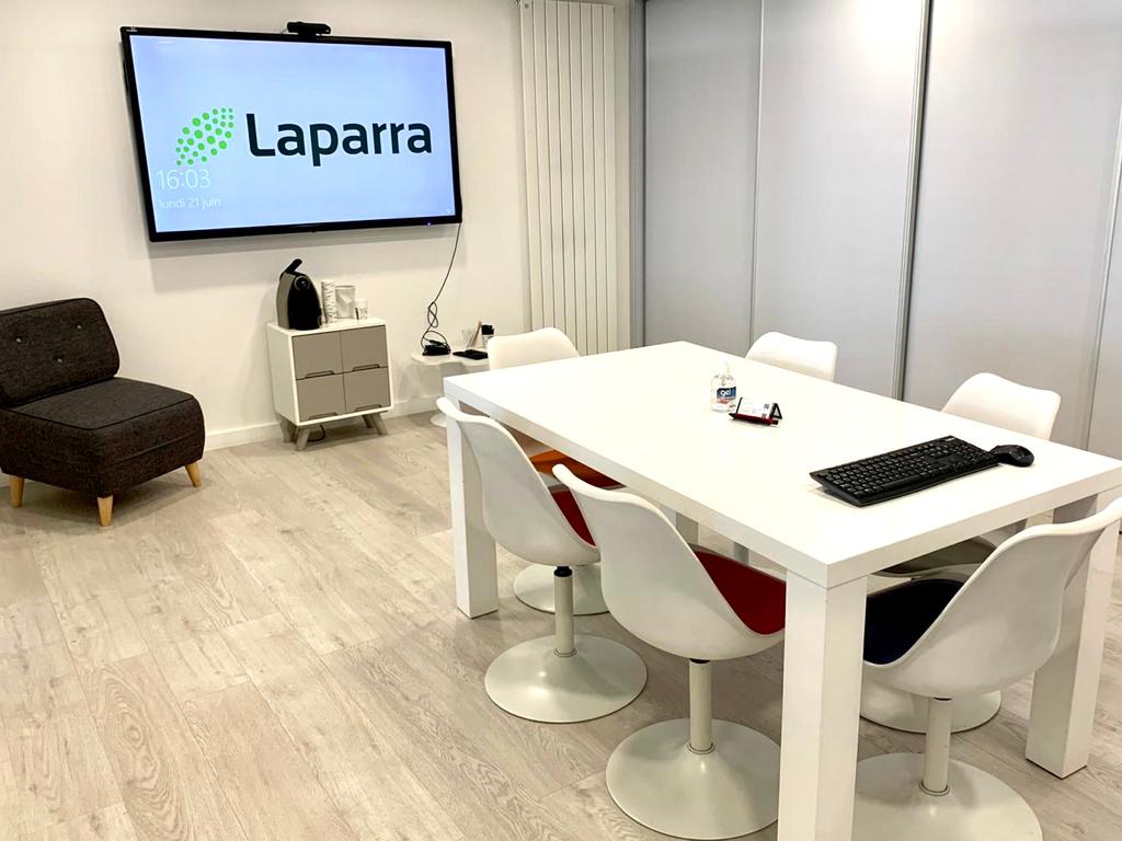 Laparra meeting room. There is an interactive screen with the company logo, table and chairs and coffee machine.